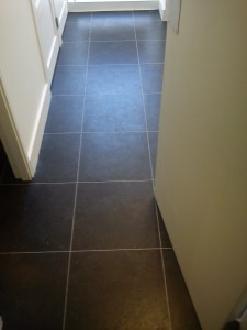 Her we have fully adhered hard vinyl tiles with feature strip to Hallway.